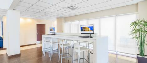A modern reception area with a long counter, several white chairs, and a large window providing a view of the outside.
