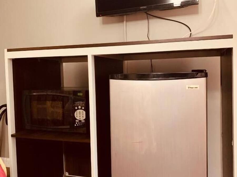 A kitchenette with a microwave, a refrigerator, and a television mounted above.