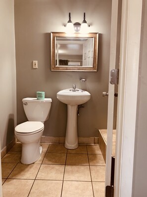 A bathroom with a toilet, sink, and mirror.