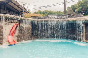 Un tobogán acuático que desemboca en una zona de piscina, con una estructura de madera al fondo.