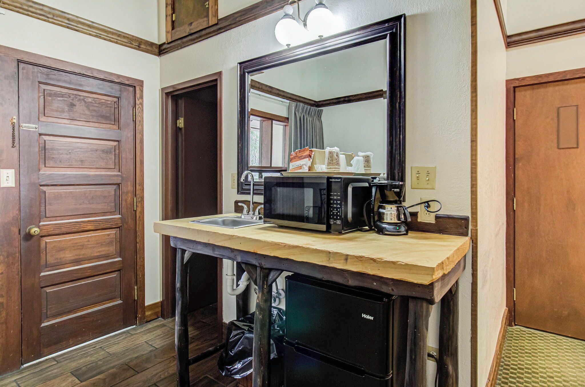 A compact kitchen with a wooden countertop, a black refrigerator, a microwave, and a coffee maker.