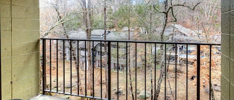 A balcony with a view of a wooded area and houses.