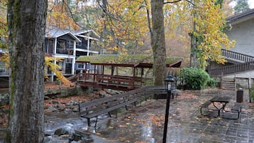 A park with a stone pathway, benches, picnic tables, and a bridge.