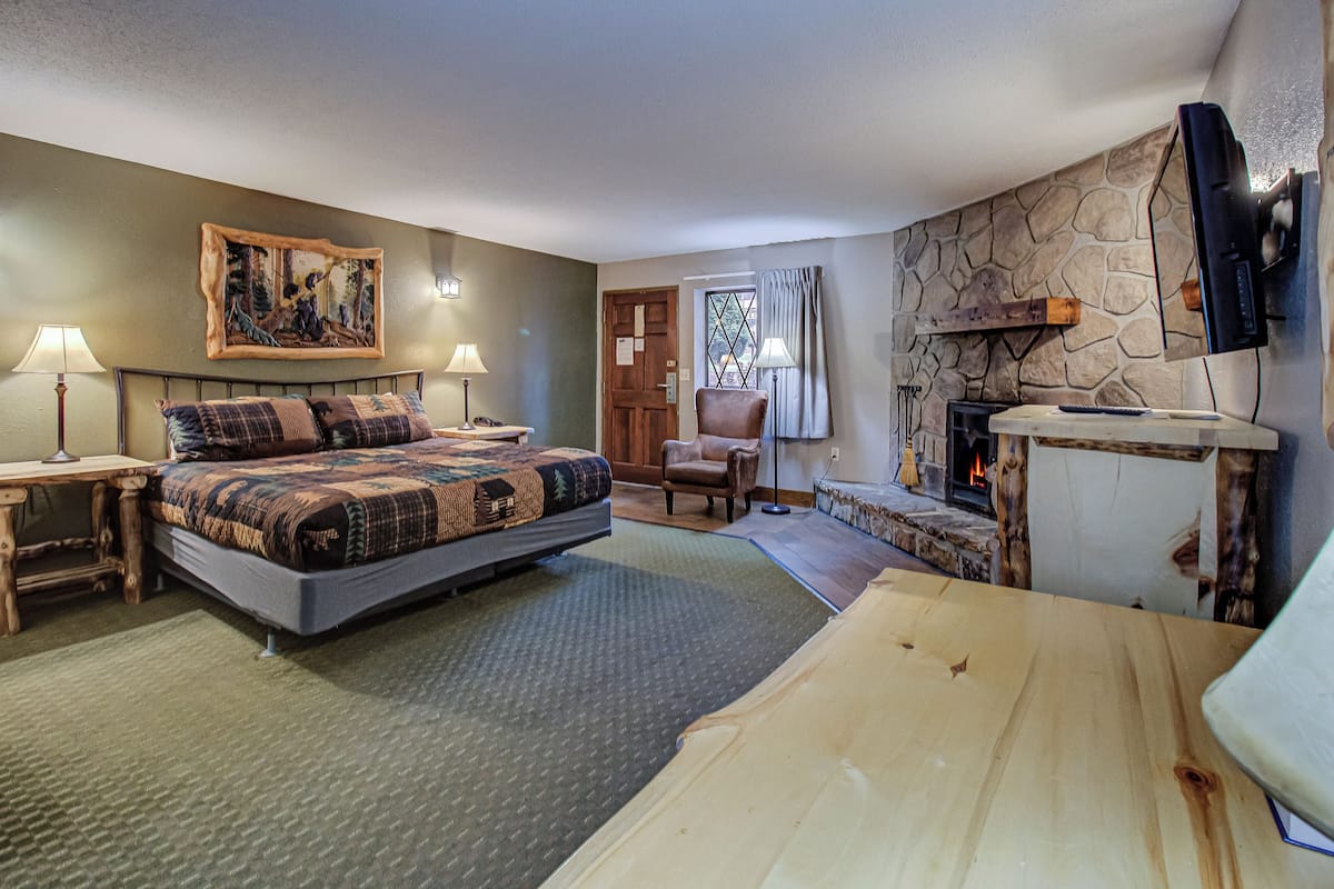 A bedroom with a bed, a chair, a fireplace, and a television.