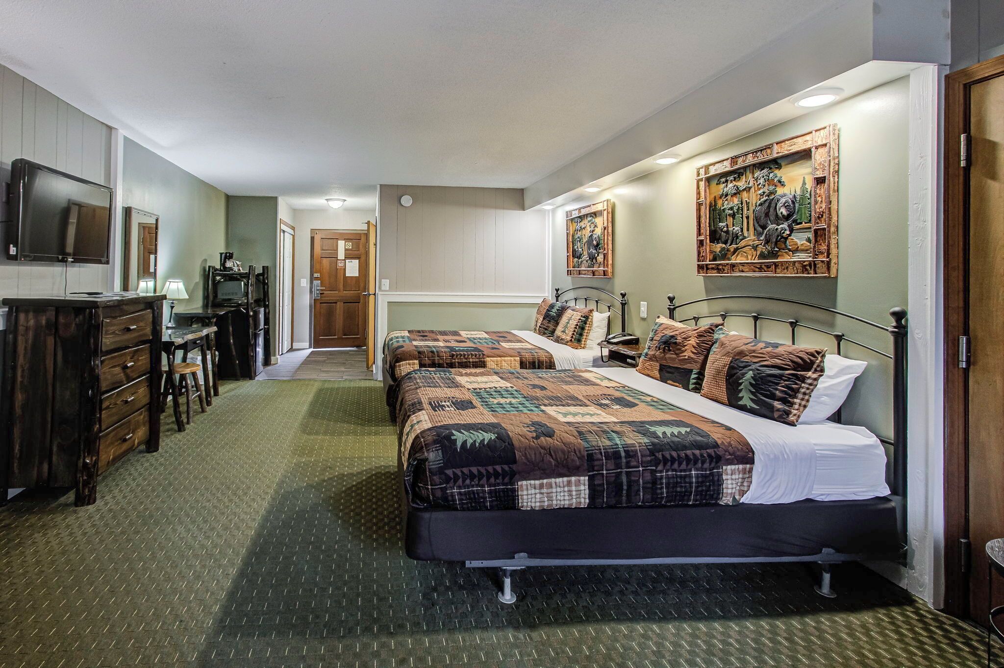 A hotel room with two beds, a desk with a chair, a TV, and a painting on the wall.