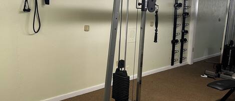 A gym with exercise equipment, a bench, and a mirror.