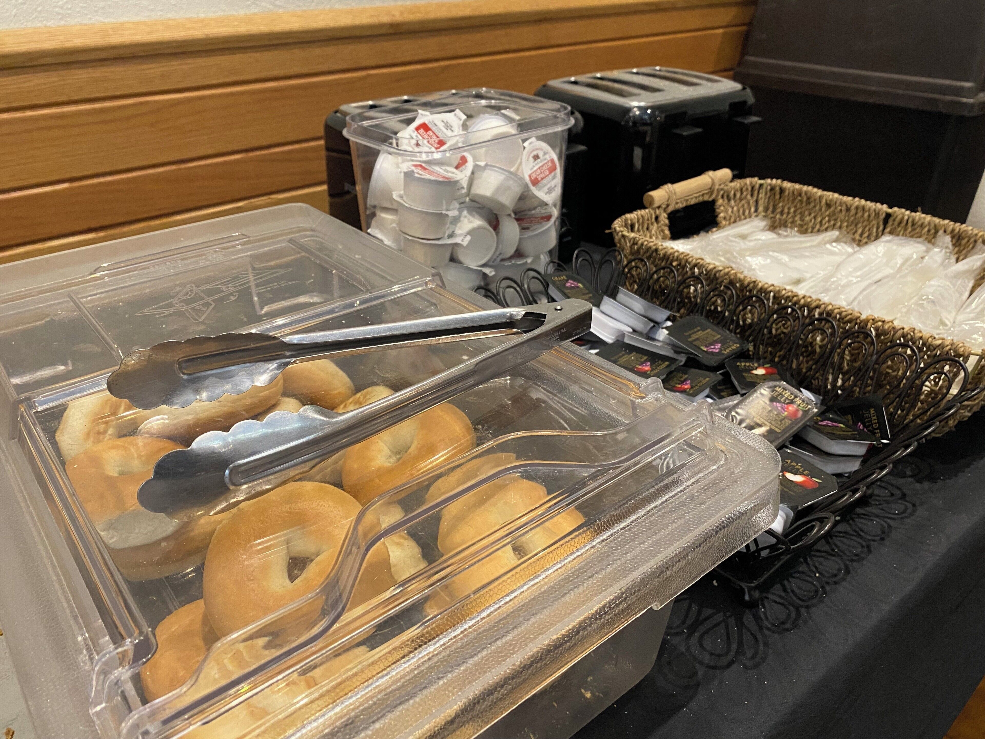 Un bufé de desayuno con bagels, un dispensador de café y un tostador.