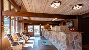 A lobby with wooden beams, stone counter, and seating area. - Brookside Lodge (Gatlinburg)