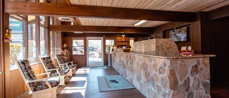 A lobby with wooden beams, stone counter, and seating area.
