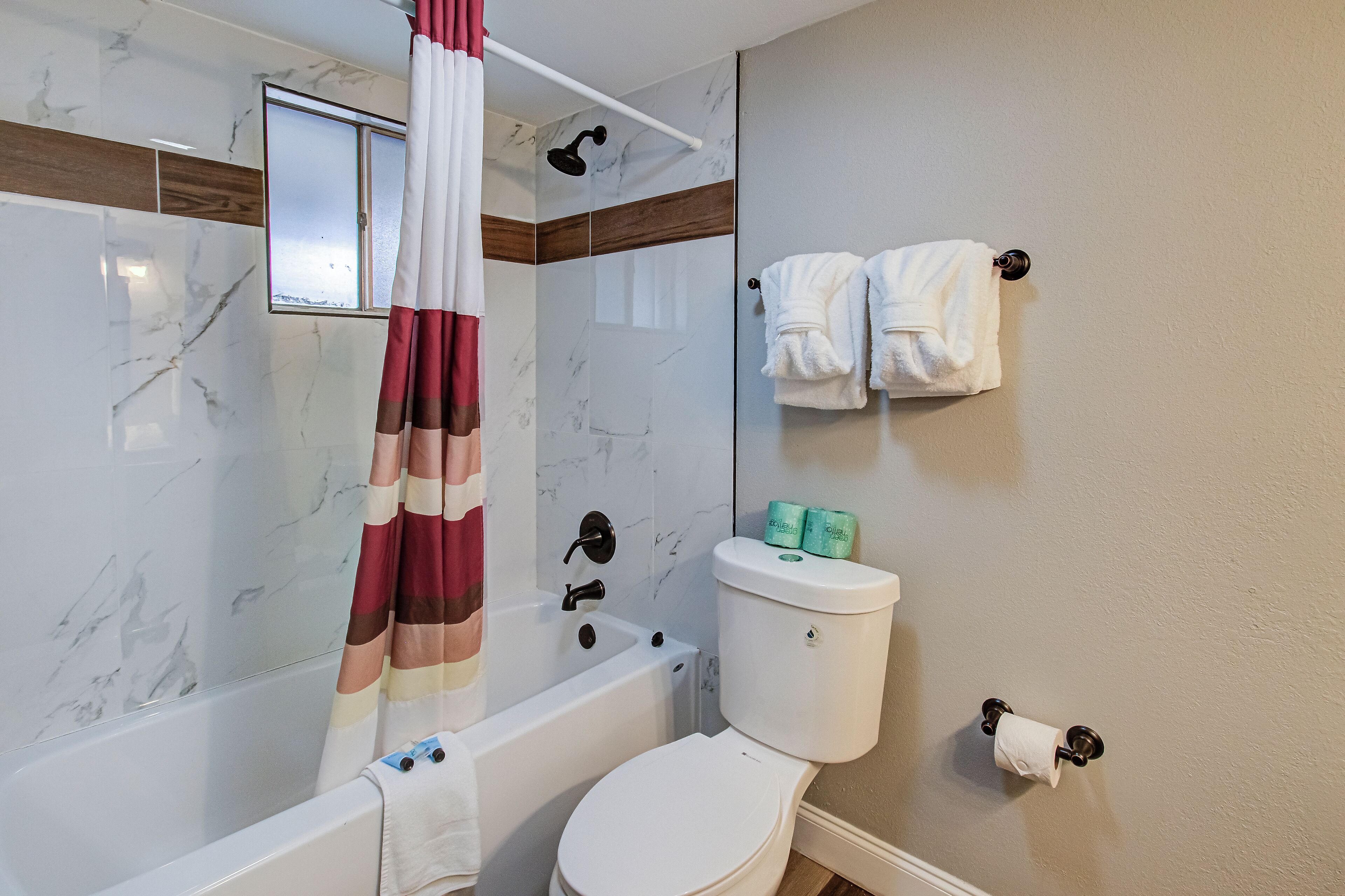 A bathroom with a bathtub, toilet, and shower curtain.
