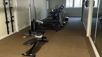 Un gimnasio con equipo cardiovascular, máquinas de pesas y un banco.