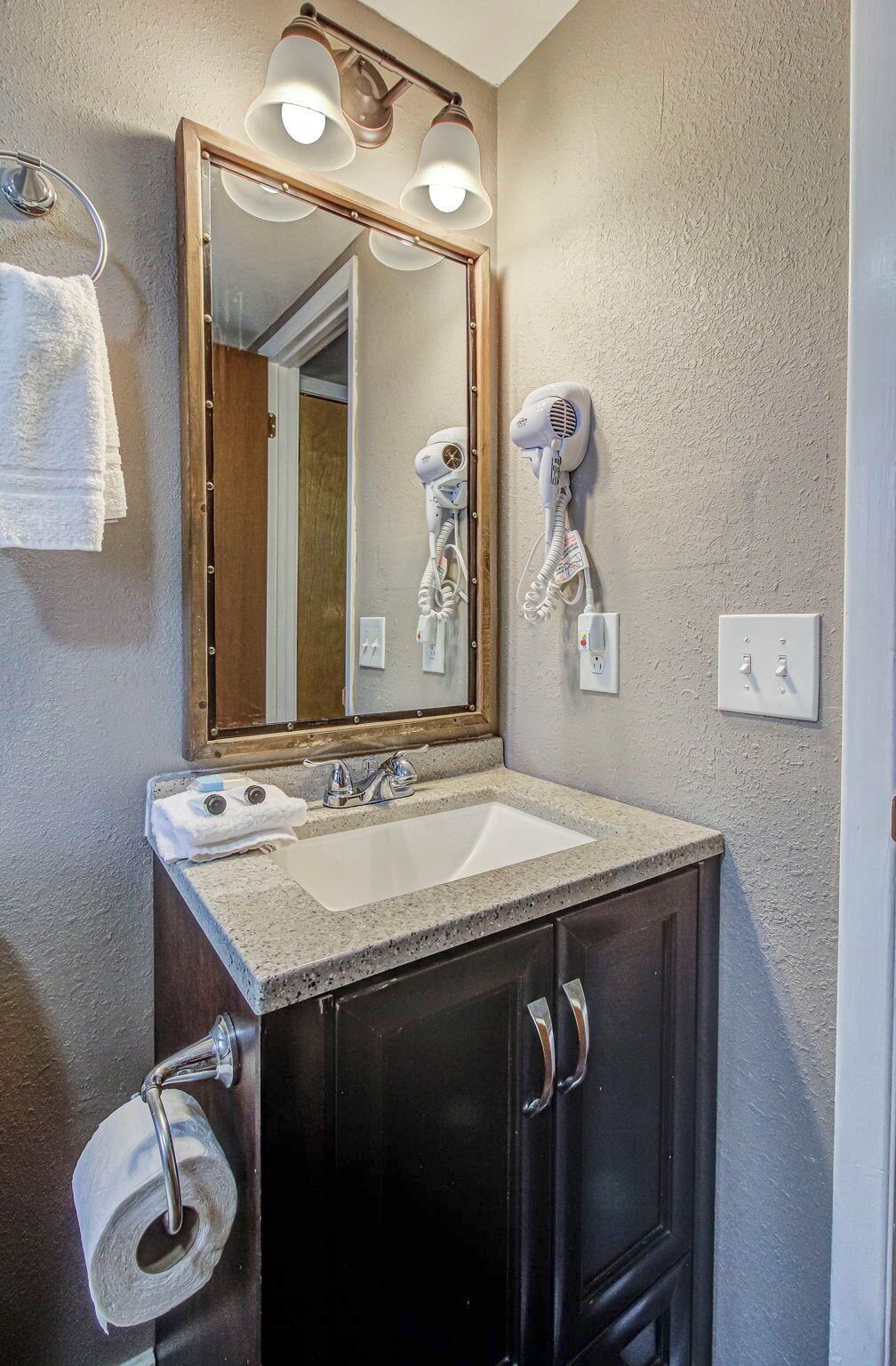 A bathroom with a double sink, a mirror, a hairdryer, and a towel rack.