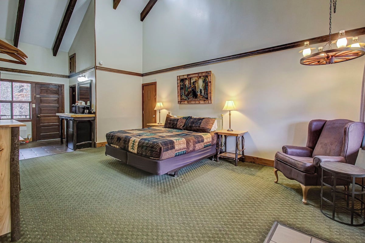 A bedroom with a large bed, a desk, a chair, and a painting on the wall.
