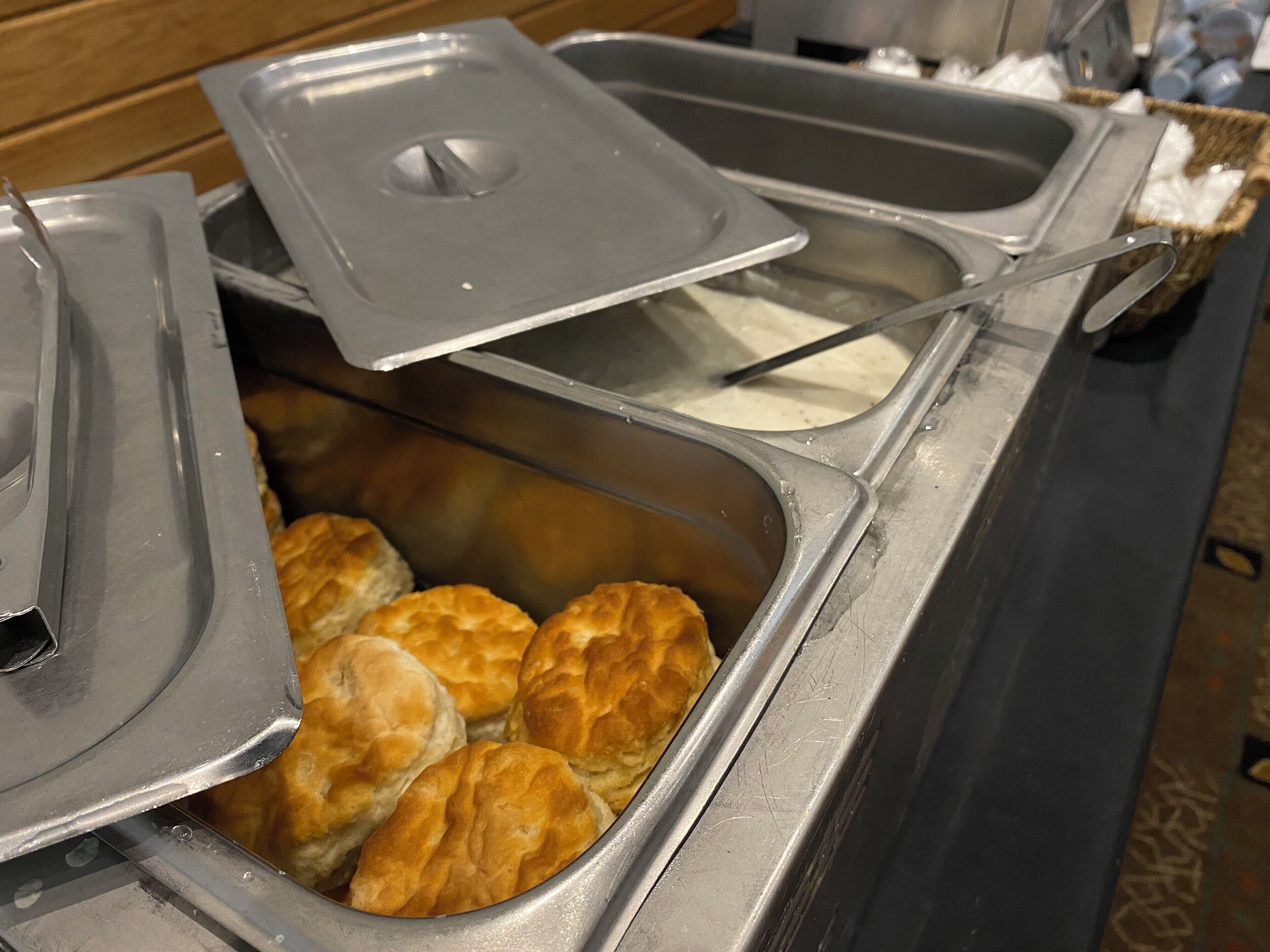A buffet with a variety of food items, including biscuits and a container with a lid.