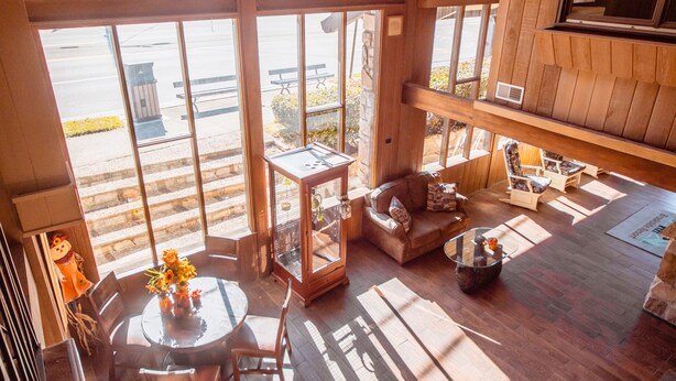 A spacious room with large windows, wooden flooring, and a high ceiling. - Brookside Lodge (Gatlinburg)