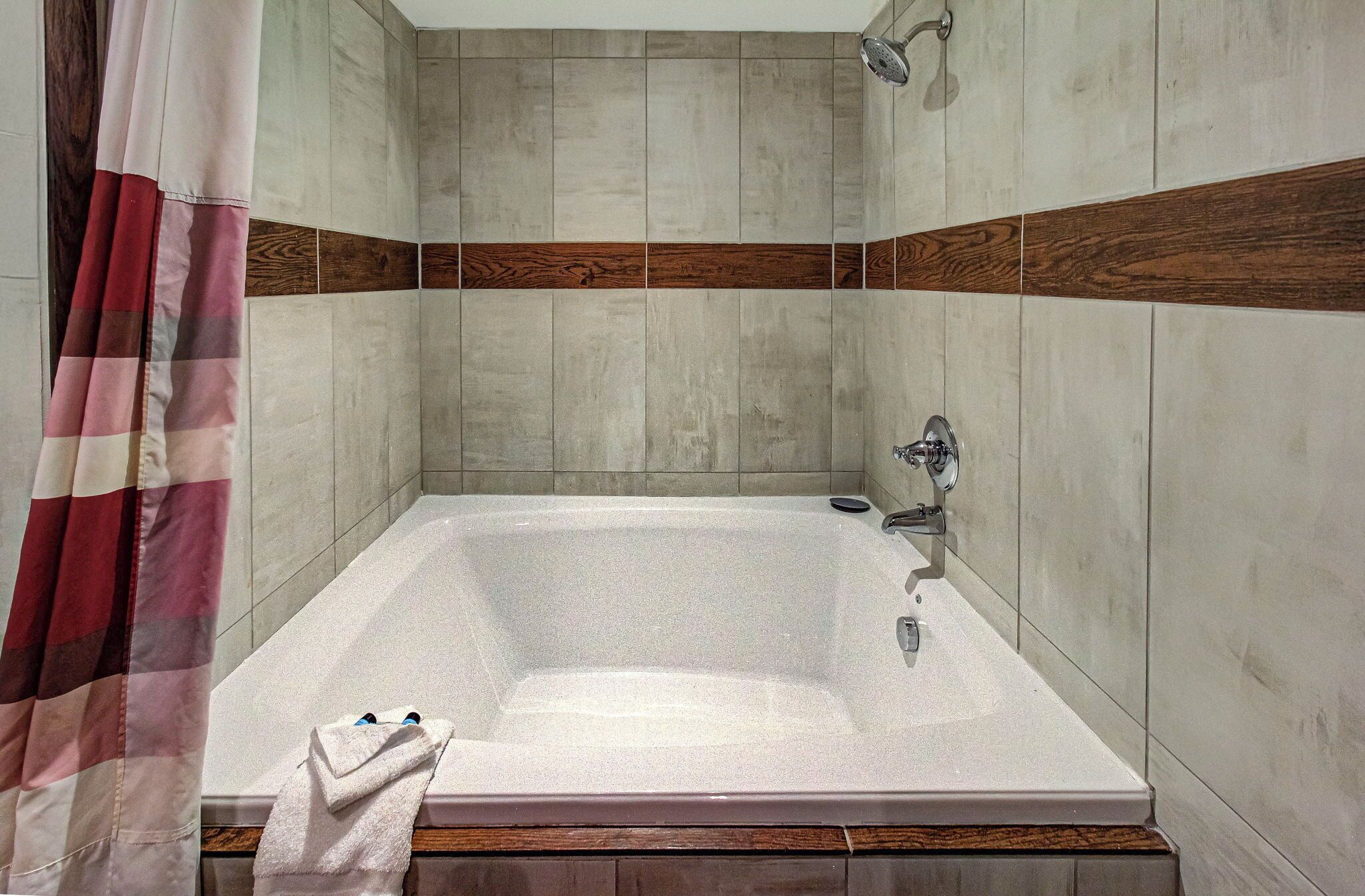 A modern bathroom with a large bathtub, wooden accents on the walls, and a showerhead.