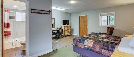 A bedroom with a bed, a desk, a chair, a wardrobe, and a bathroom.