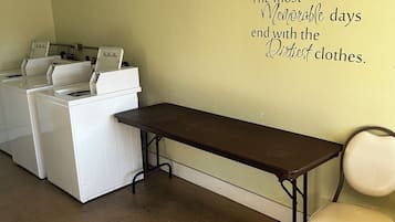 Un lavadero con una mesa y sillas, un tendedero de pared y un adhesivo decorativo con una cita.