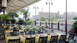 An outdoor dining area with tables and chairs, a covered section, and a view of buildings in the background. - Hotel Crown Palais Kokura (Kitakyushu)
