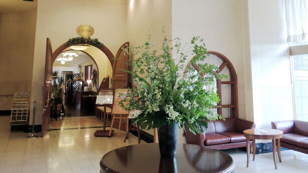 A lobby with a reception desk, seating area, and a large vase with flowers. - Hotel Crown Palais Kokura (Kitakyushu)