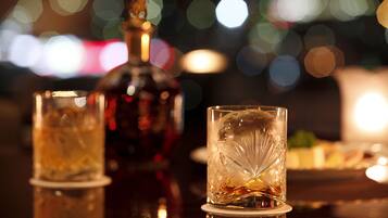 A bar setting with a bottle and two glasses on a reflective surface.