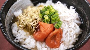 A bowl of white rice with toppings including shredded seaweed, sliced green onions, and a piece of carrot.
