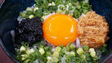 Un bol de riz, un œuf cru et divers accompagnements.