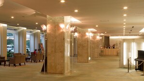 A hotel lobby with marble pillars, a reception desk, a piano, and seating areas. - Hotel Crown Palais Kitakyushu (Kitakyushu)