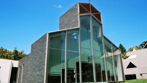 A modern building with large glass windows and a cross on top. - Hotel Crown Palais Kitakyushu (Kitakyushu)