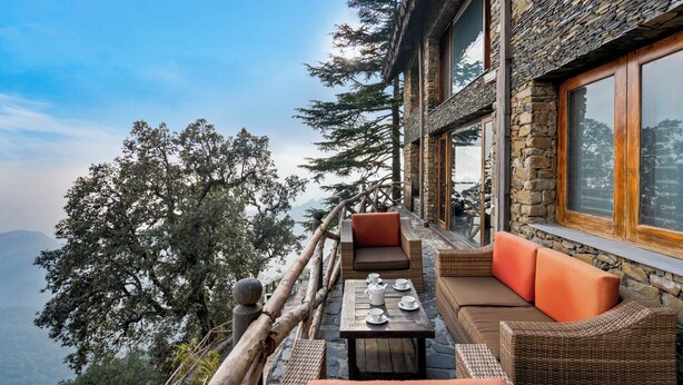 A stone building with a balcony overlooking a mountainous landscape. - Rokeby Manor (Mussoorie)