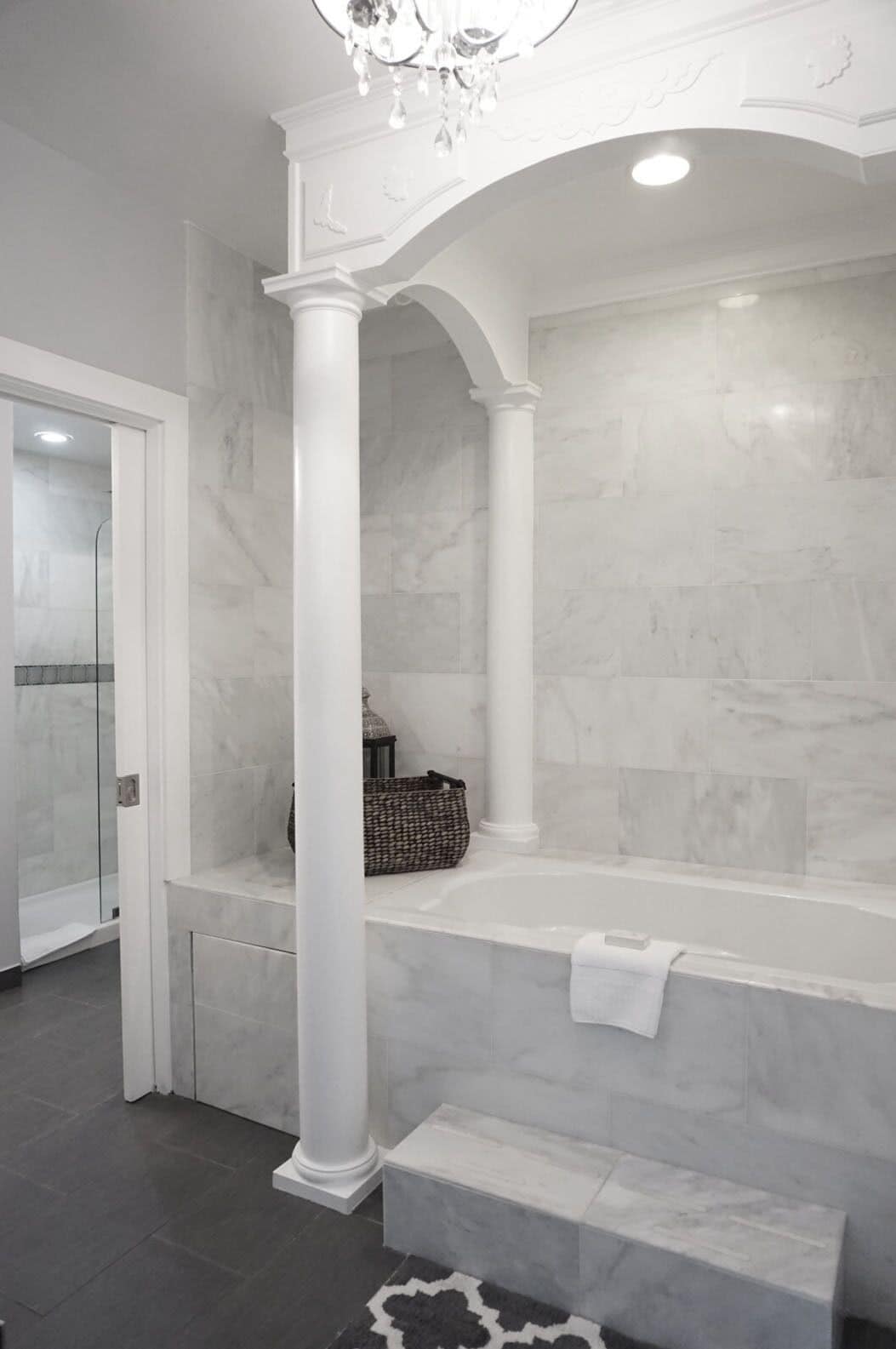 A bathroom with a marble floor, a bathtub, and a shower area.