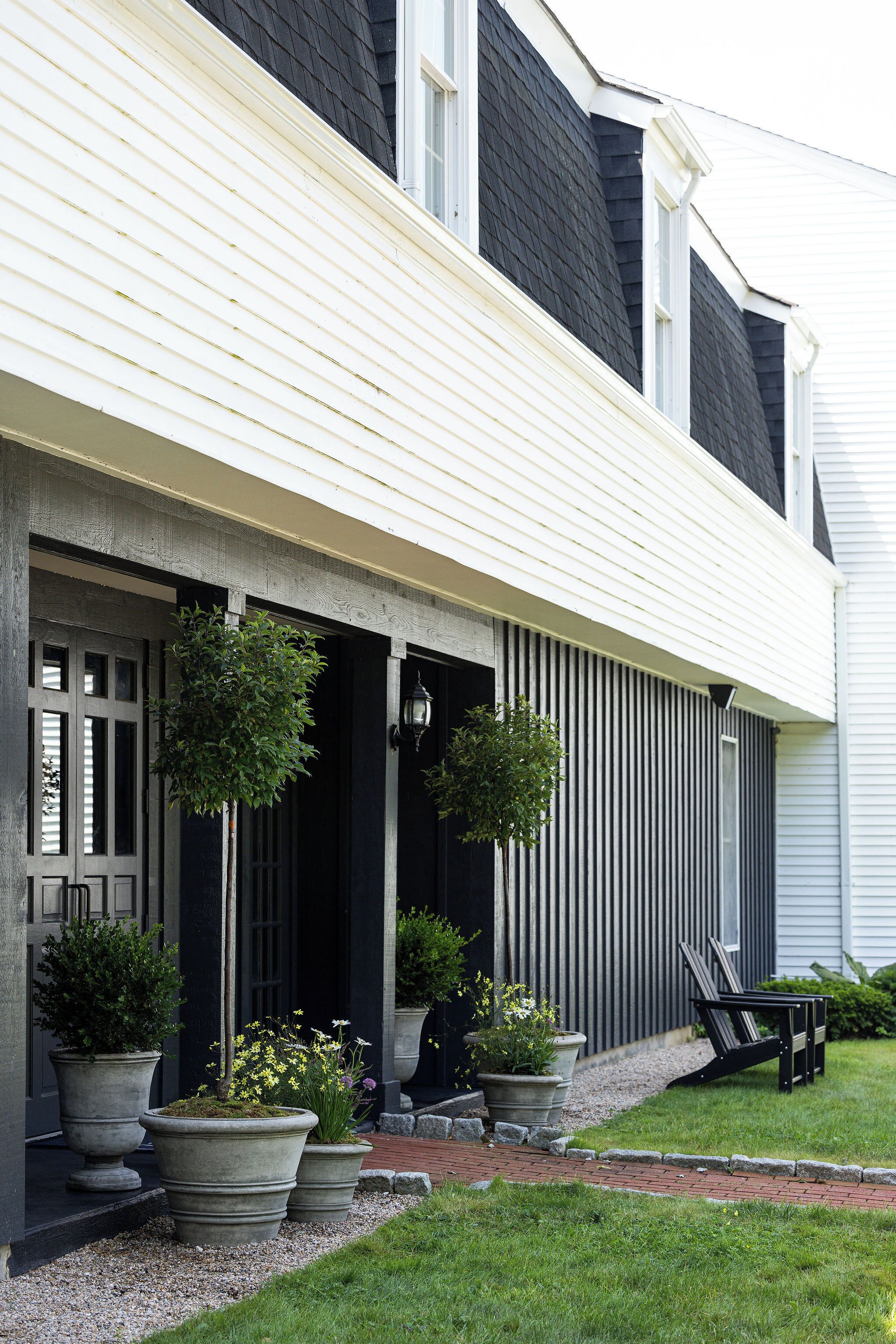 A house with a porch, large potted plants, and a bench.