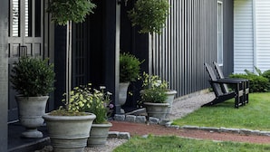 A house with a porch, large potted plants, and a bench.