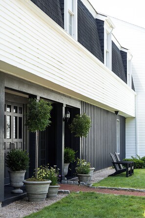 A house with a porch, large potted plants, and a bench.