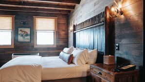 A wooden room with a bed, a nightstand, and a wall-mounted lamp.