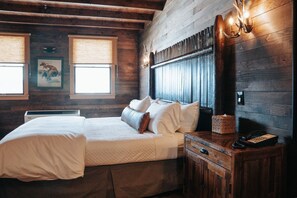 A wooden room with a bed, a nightstand, and a wall-mounted lamp.