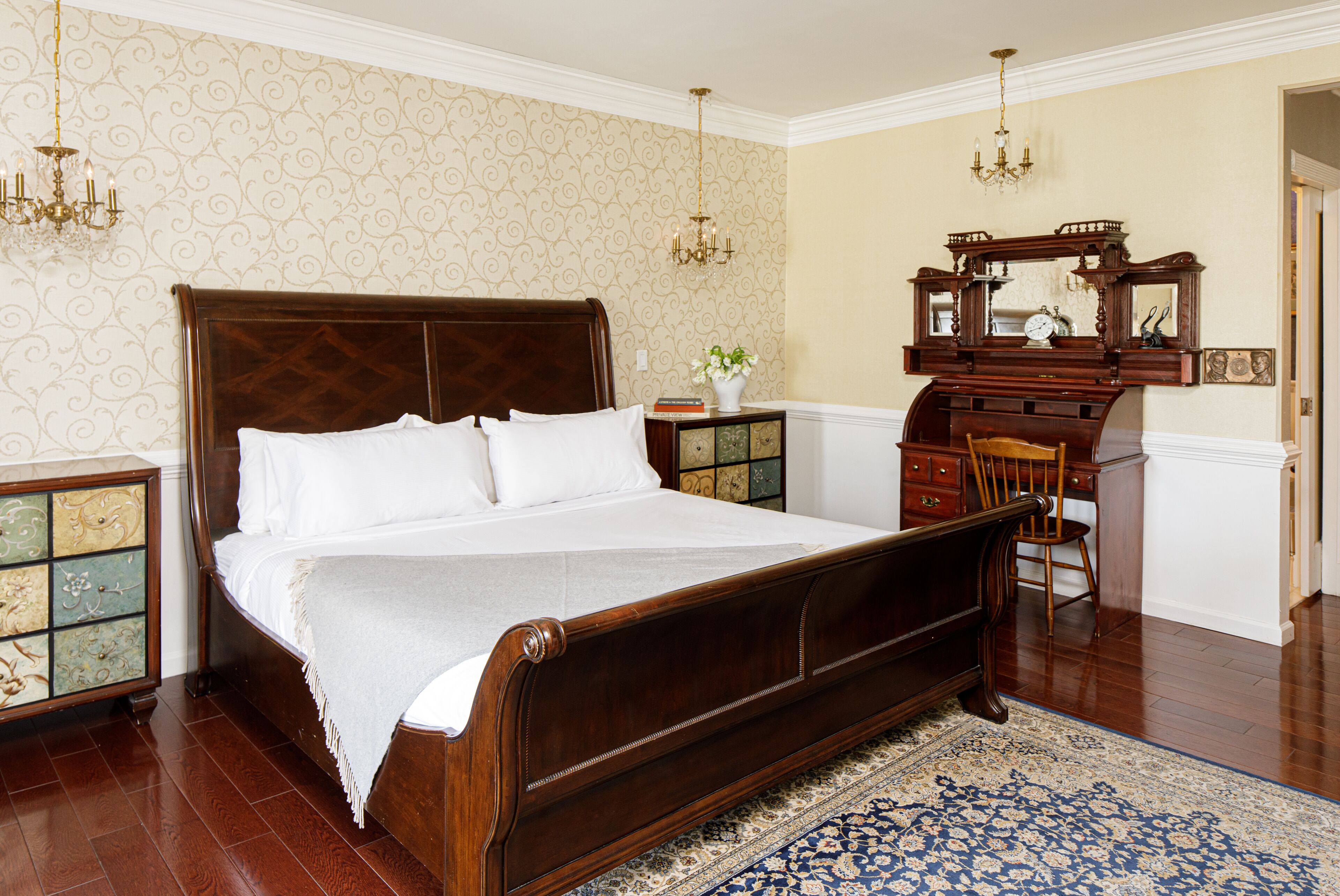 A bedroom with a large wooden bed, a nightstand, a dresser, and a mirror.