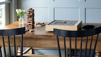 A wooden table with a jigsaw puzzle, two black chairs, and a vase with flowers.