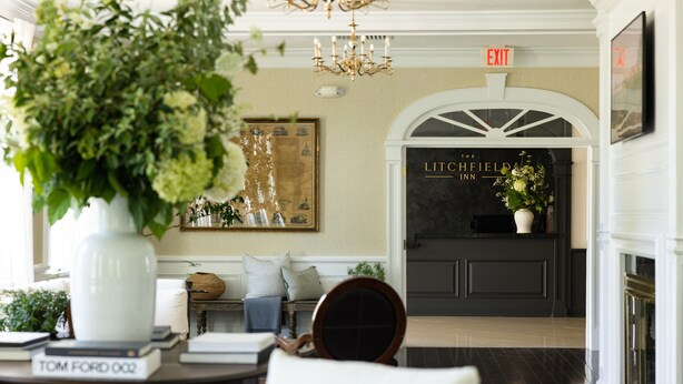 A lobby with a chandelier, a reception desk, and a sign indicating an exit. - The Litchfield Inn (Litchfield)