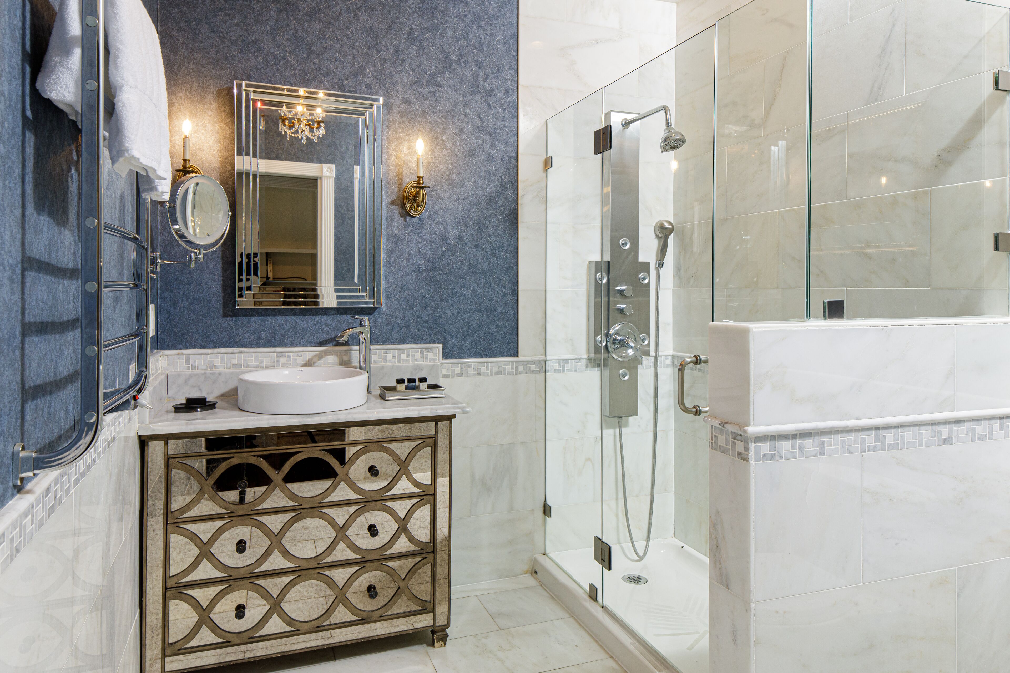 Une salle de bain avec une douche à parois de verre, un lavabo blanc et un meuble-lavabo doté de tiroirs décoratifs.