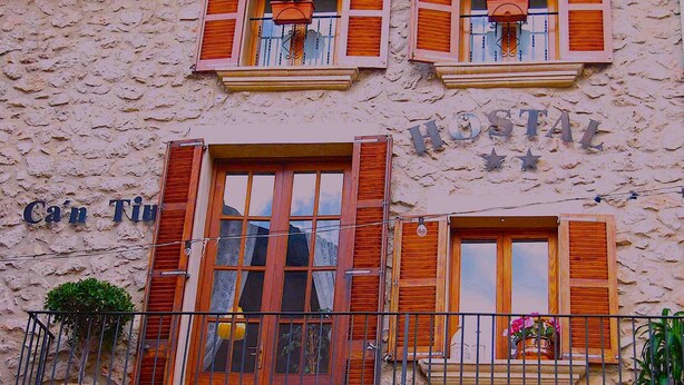 A building with a stone facade, wooden shutters, and a sign that reads "Ca'n Tiu".
