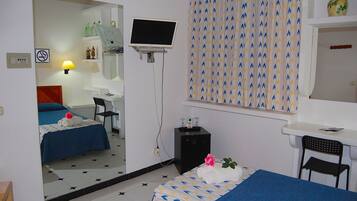 Una habitación de hotel con dos camas, un escritorio, una silla, un televisor y un espejo.