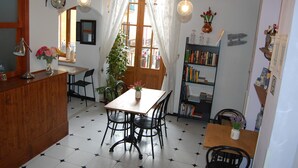 A cozy dining area with a wooden table and chairs, a bookshelf, and a window with curtains.