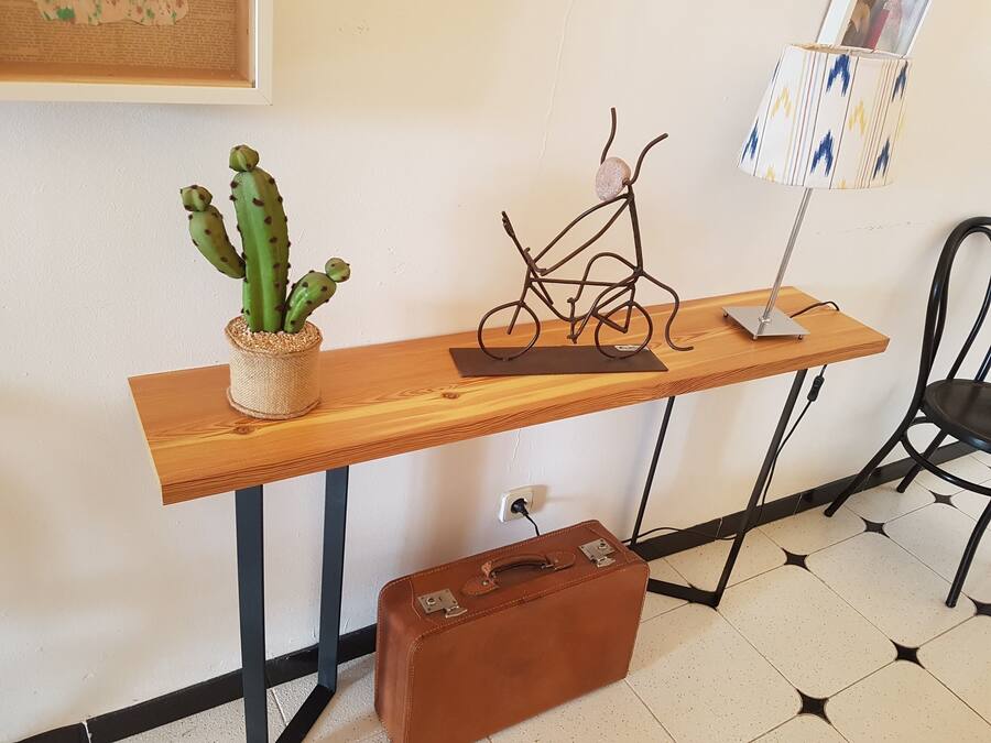Une table en bois, sur laquelle on peut voir un cactus, un vélo et une lampe.