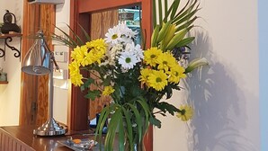A reception desk with a clock, a vase of flowers, and a wooden panel.