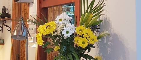 A reception desk with a clock, a vase of flowers, and a wooden panel.