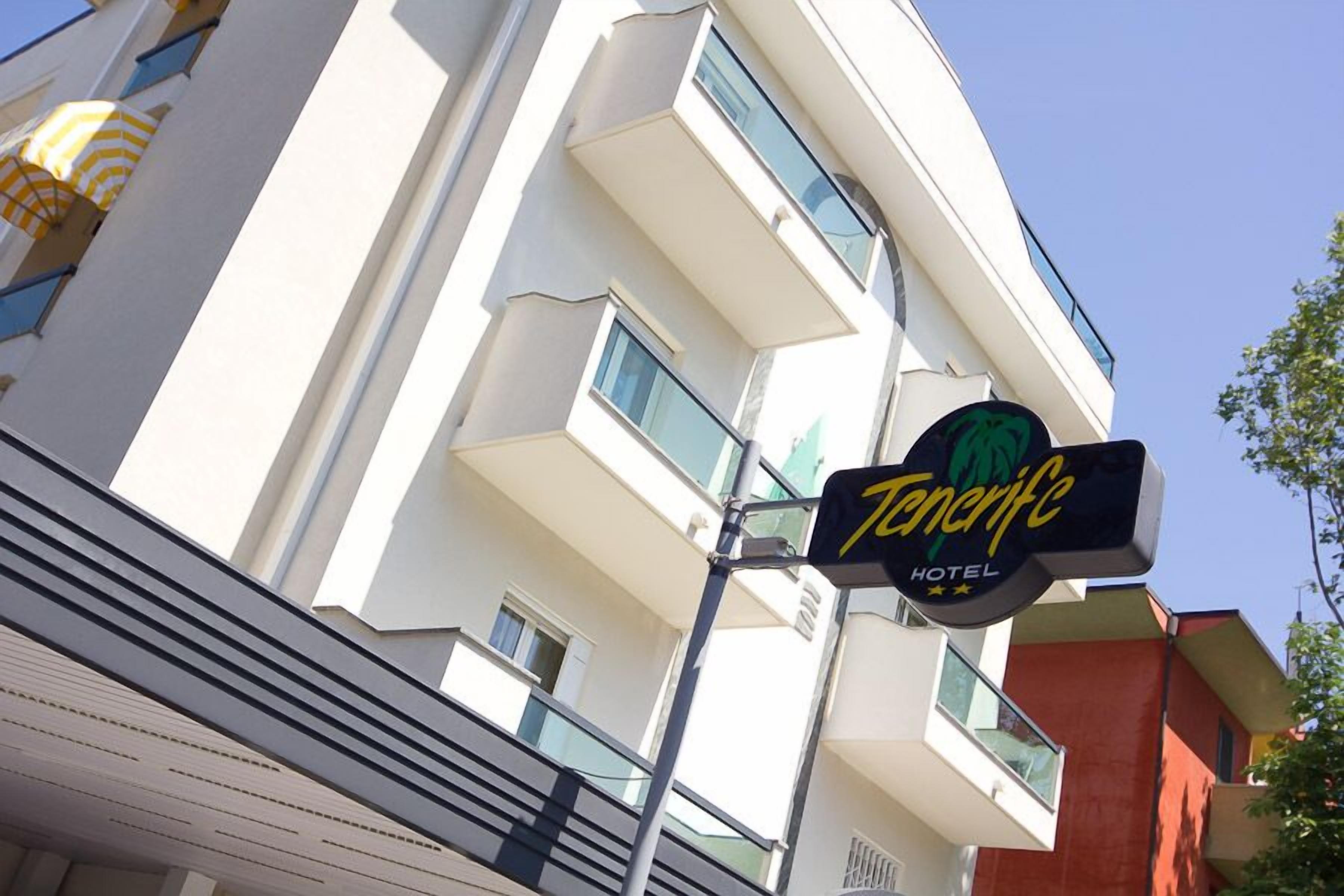 A hotel sign for 'Tenerife Hotel' with a modern building in the background.