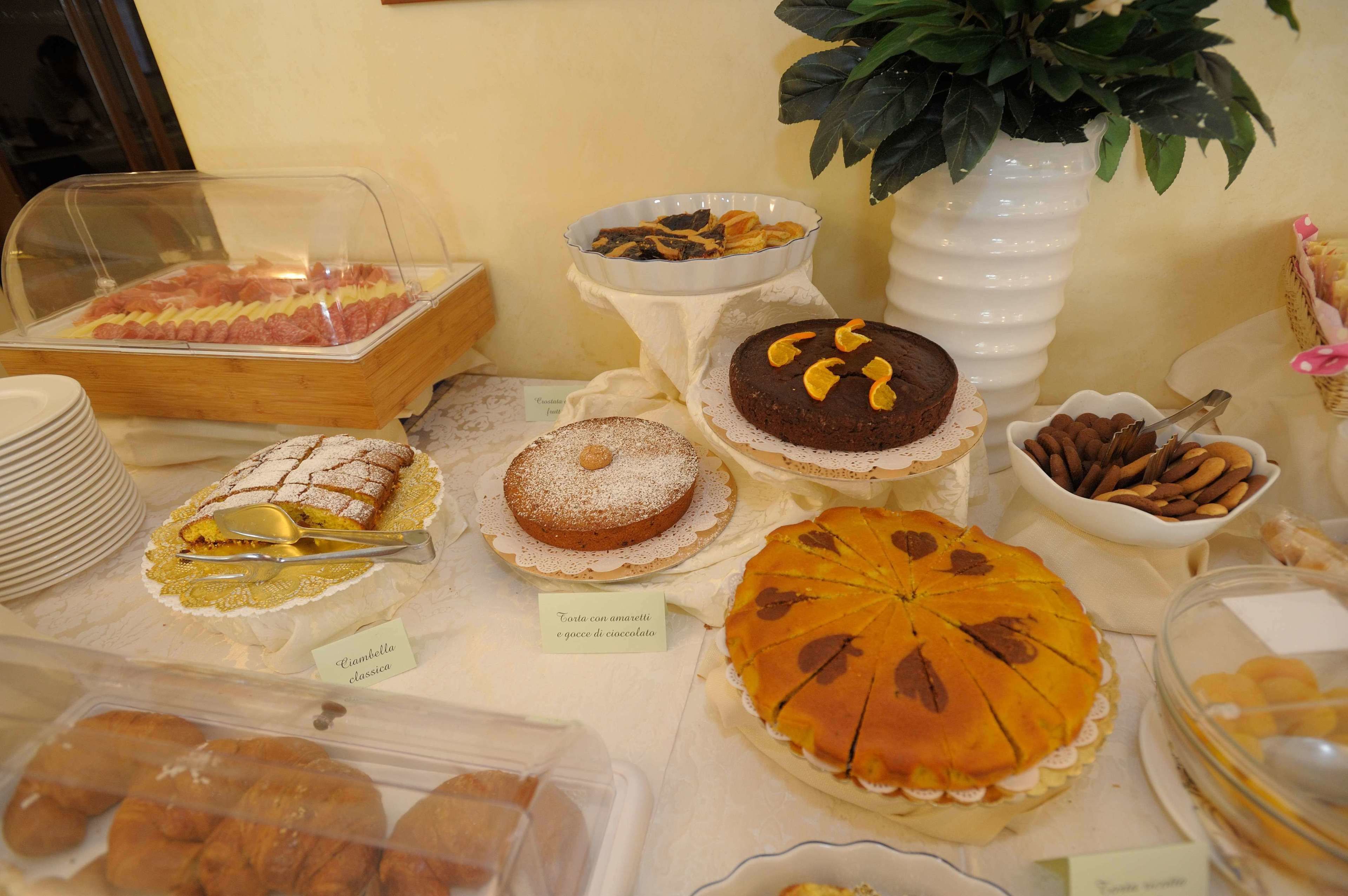 A variety of desserts and pastries displayed on a table, including cakes, tarts, and a chocolate cake with a decorative topping.