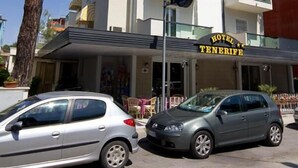 Un hotel llamado "Hotel Tenerife" con un estilo arquitectónico moderno, que cuenta con balcones y un letrero llamativo.