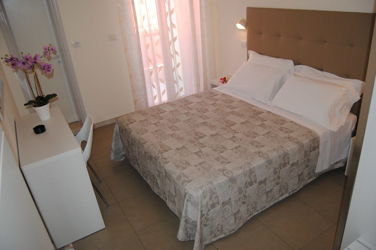 Ein Schlafzimmer mit einem Bett, einem Nachttisch und einer Topfpflanze.